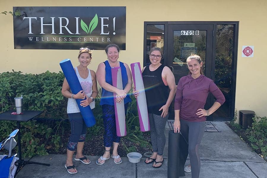 Jenna Dodge with 3 class participants standing in front of Thrive! wellness center